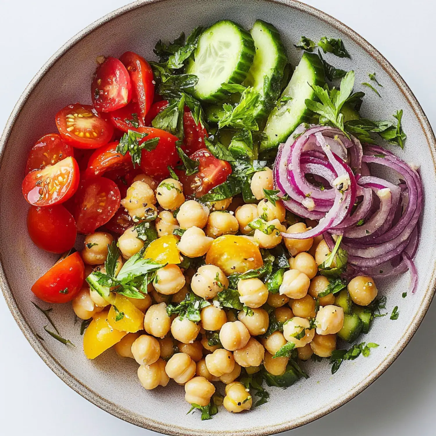 A colorful bowl with chickpeas, cucumbers, tomatoes, red onions, and parsley.