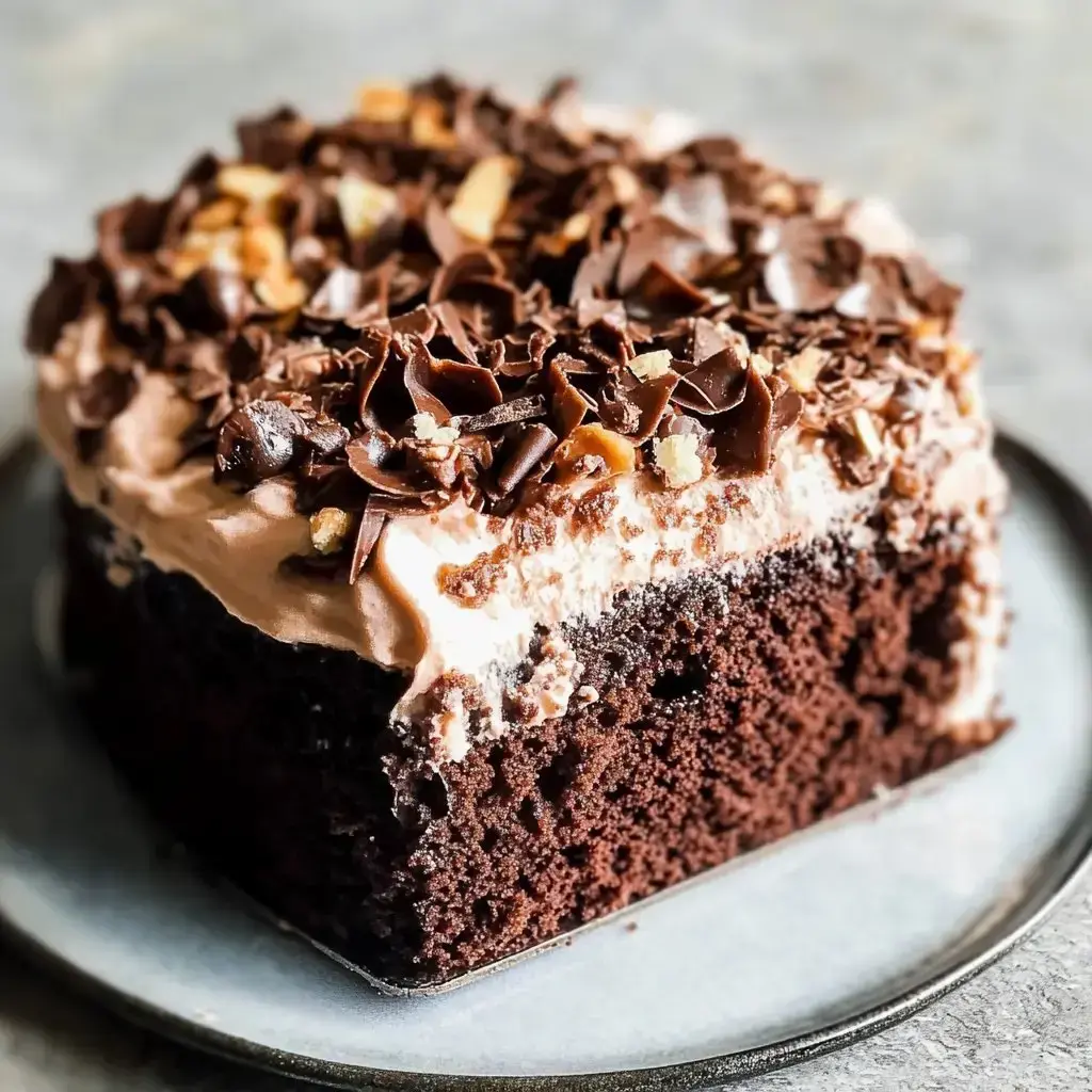 A rich and indulgent chocolate cake covered with caramel, whipped cream, and crushed candy bars on a plate.