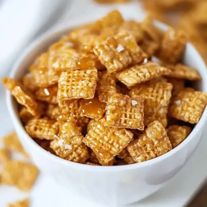 Golden Crispix cereal coated in glossy caramel and topped with salt in a bowl.