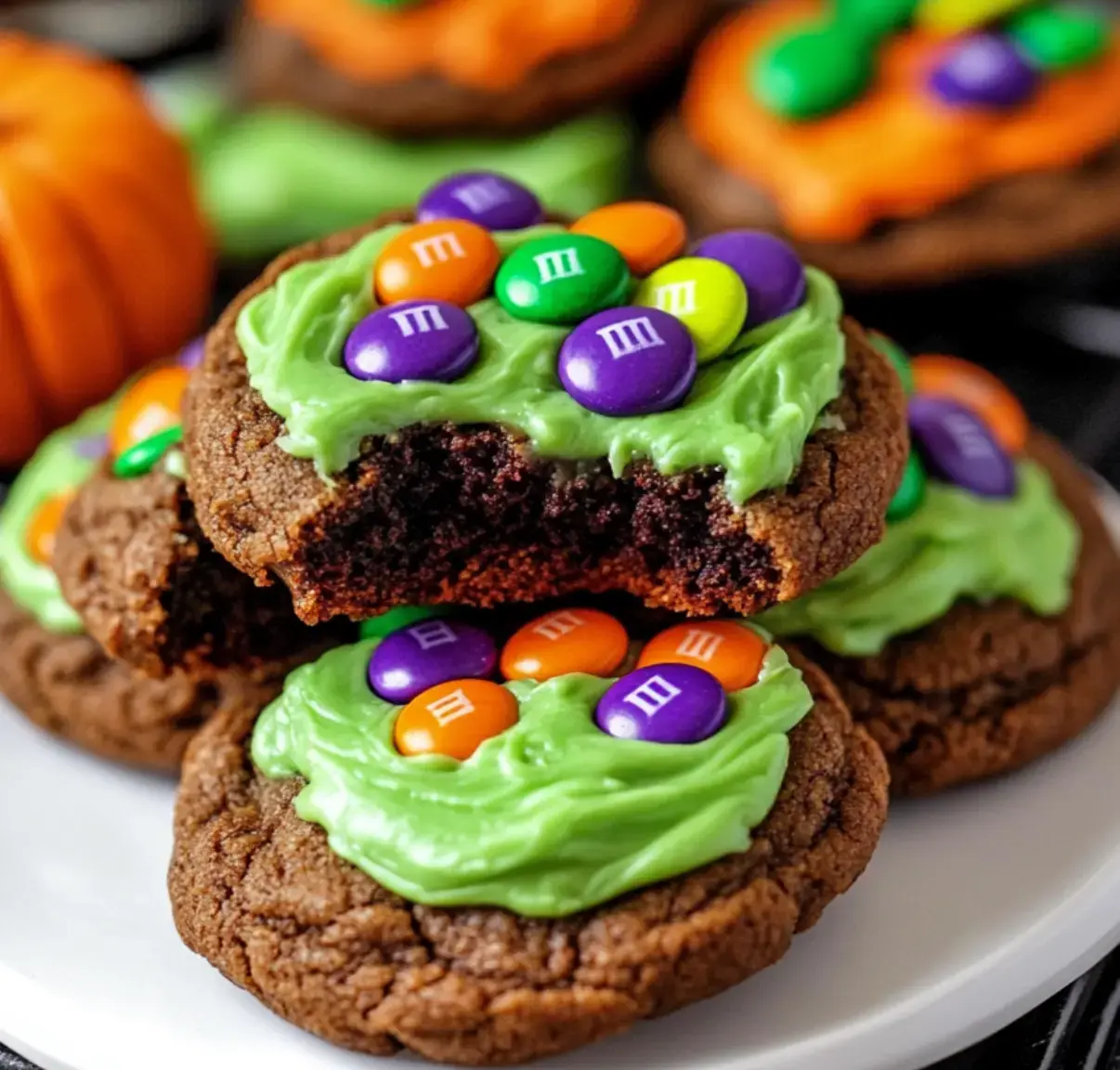 Chocolate cookies on a plate decorated with bright green filling and colorful candies, perfect for Halloween fun.