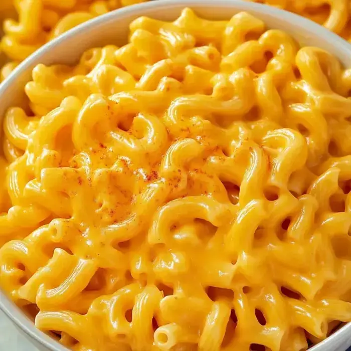 A creamy bowl of macaroni and cheese topped with paprika.