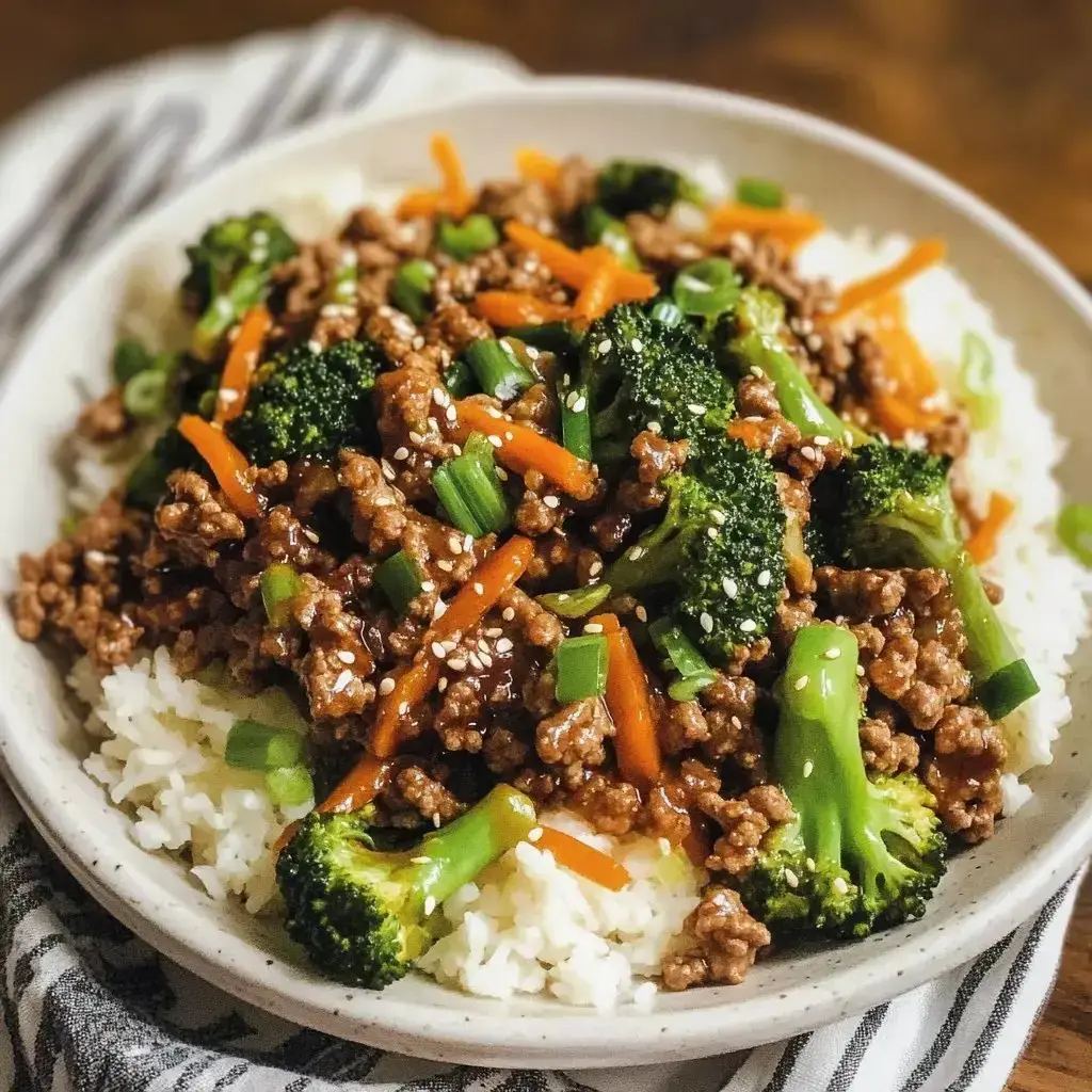 Rice topped with stir-fried ground beef, broccoli, carrots, and green onions, finished with sesame seeds.