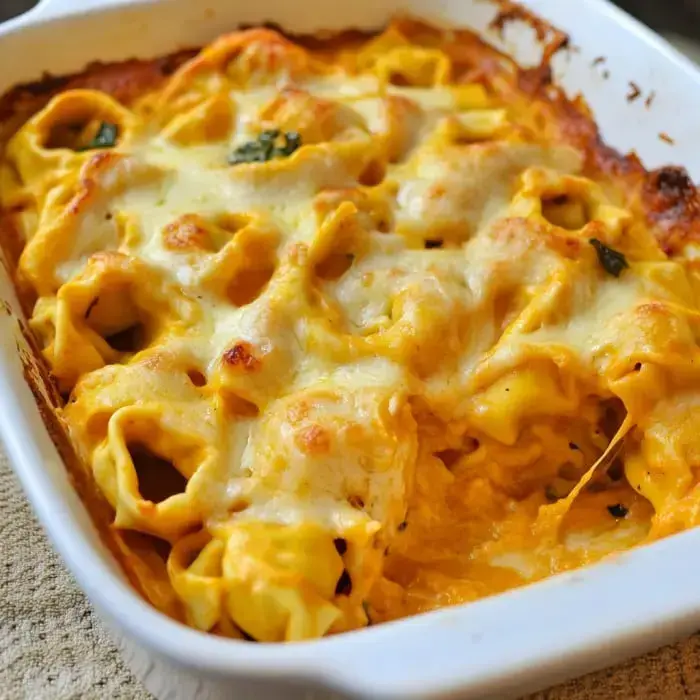 Baked tortellini pasta in a creamy pumpkin cheese sauce with fresh herbs on top.