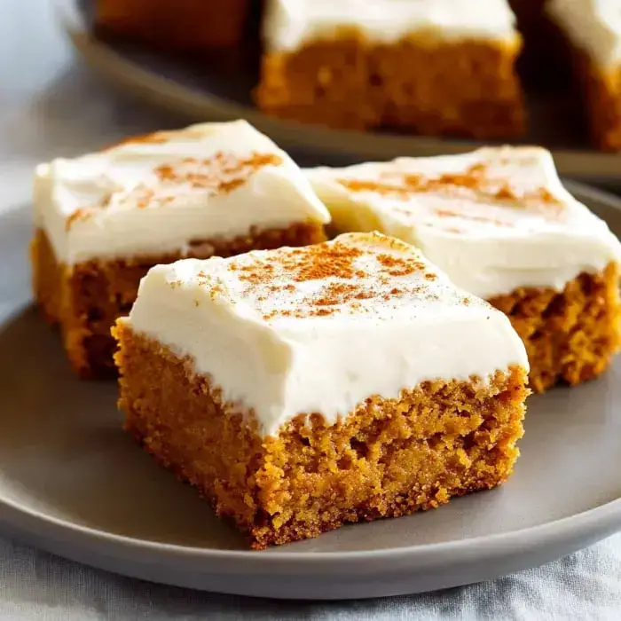 Soft pumpkin bars with a layer of cream cheese frosting lightly dusted with cinnamon.