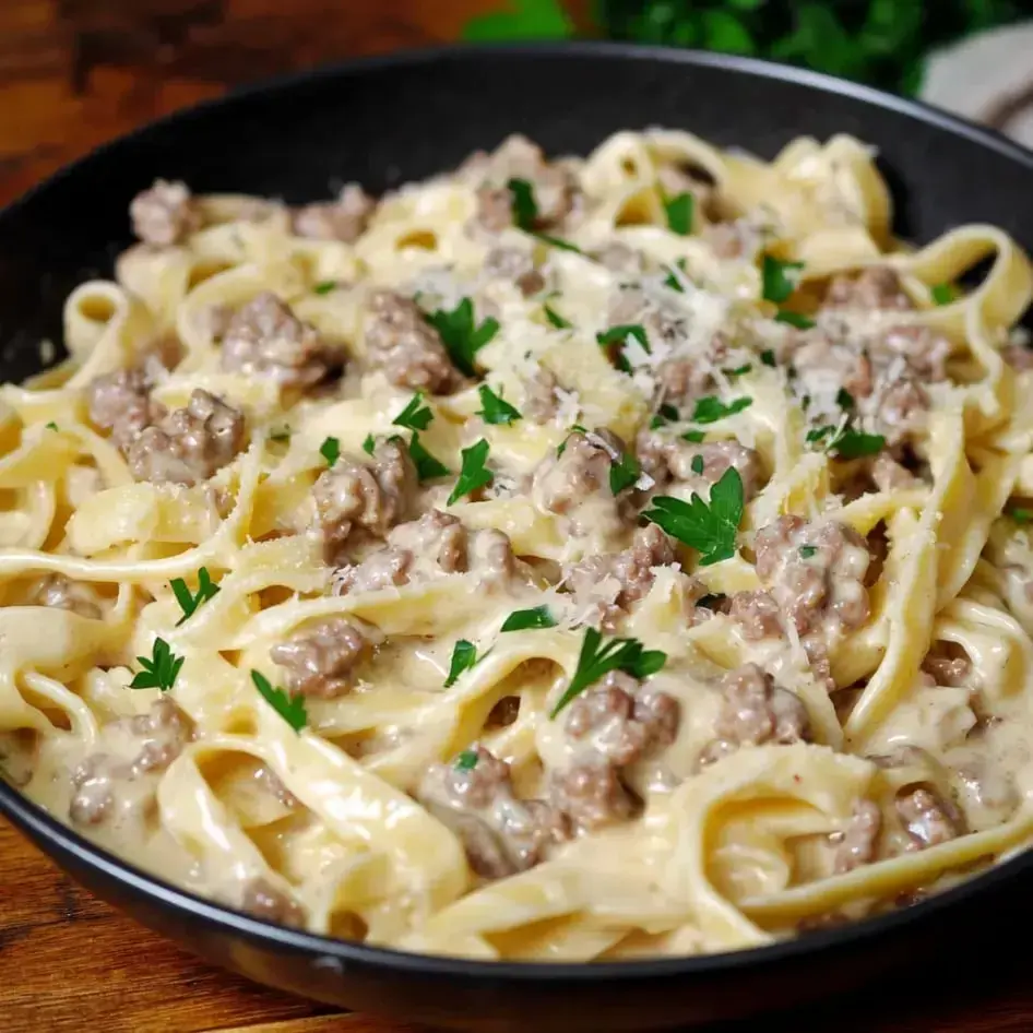 A plate of creamy pasta with beef and mushrooms, topped with fresh parsley.