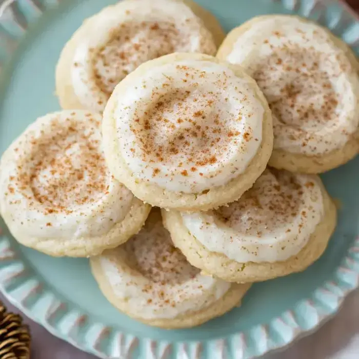A batch of fluffy sugar treats with smooth topping and cinnamon sprinkles arranged on a pale blue dish.