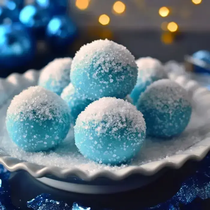 You’ll see blue, sugar-dusted round treats on a plate, the scene dressed up with blue ornaments and cozy lights in the background.