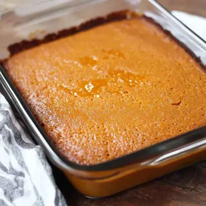 Golden sweet potato cornbread fresh out of the oven in a glass dish on wood.