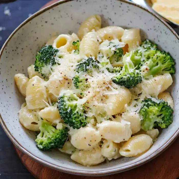 A bowl packed with creamy pasta and broccoli, sprinkled with fresh Parm on top.