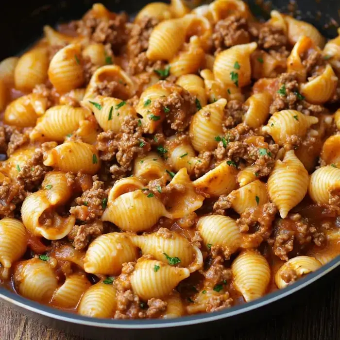 A big skillet full of shell noodles tossed with beef and a tomatoey sauce, fresh parsley sprinkled on top.