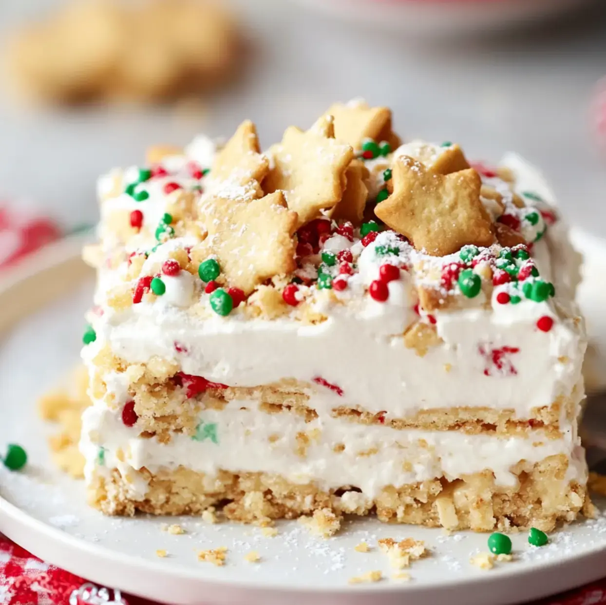 A dessert square loaded with whipped cream, colorful sprinkles, and cute star cookies rests on a white plate.