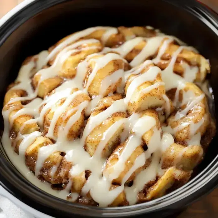 A close-up shot of cinnamon roll bites in a bowl covered with creamy frosting.