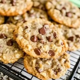 Close-up shot of golden-brown cookies with chocolate chips and crispy texture, resting on a wire rack.