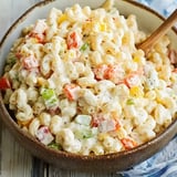 A creamy pasta dish with a mix of veggies like bell peppers and celery in a light dressing, all in a serving bowl.