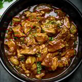 Bite-sized, juicy chicken pieces glazed in a rich, dark sauce and sprinkled with fresh herbs.