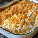 A golden helping of creamy potatoes with a crispy topping and hints of melted cheese against a cozy kitchen backdrop.