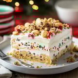 A holiday dessert slice with cookies, cherries, and bright sprinkles, served with a fork on a plate.