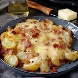 A plate of golden potatoes topped with melted cheese and crispy bacon, served on a gray dish.