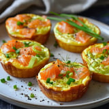 Mini savory quiches filled with smoked salmon, green onions, and herbs, served on a dish.