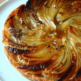 A beautifully spiraled caramelized onion tart on a plate.